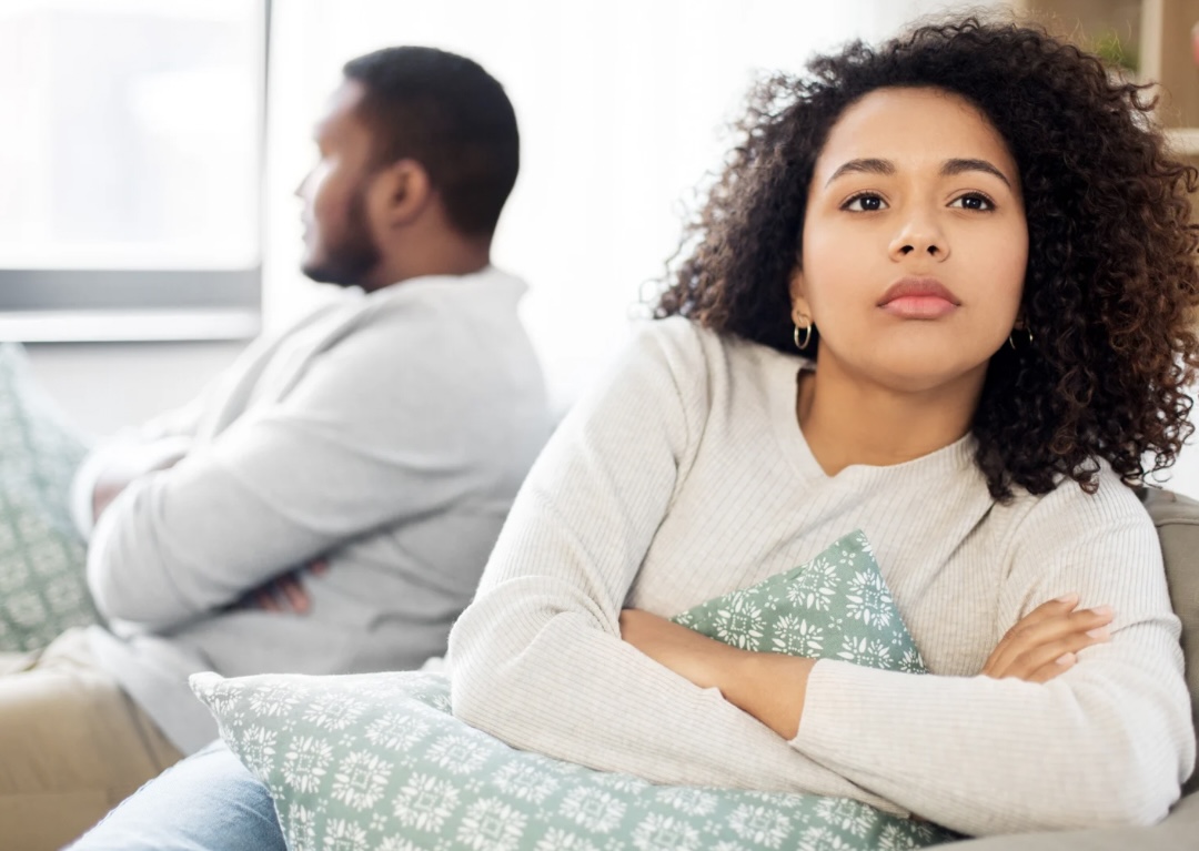 Couple feeling emotionally distant while sitting together on a couch.